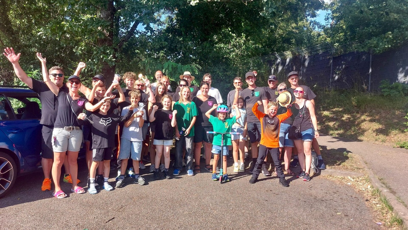 Fahrer und Eltern jubeln auf einem Gruppenbild nach einem erfolgreichen Renntag.