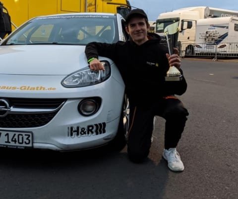 Foto von Adrian nach seinem 2. Platz beim Bundesendlauf im Youngster Cup, mit Pokal und einem der Rennfahrzeuge.